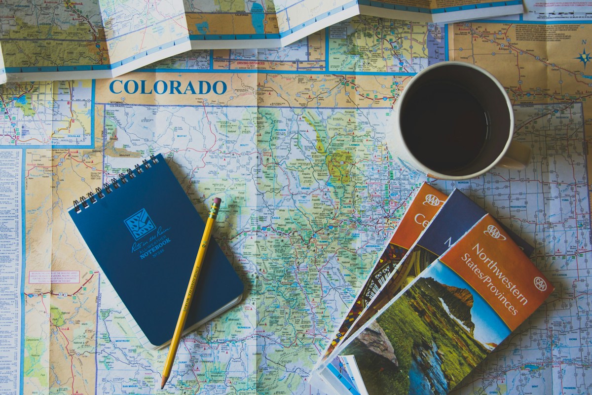 Travel guidebooks and a blue notebook spread across a road map